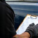 Detailer assessing a car with a clipboard